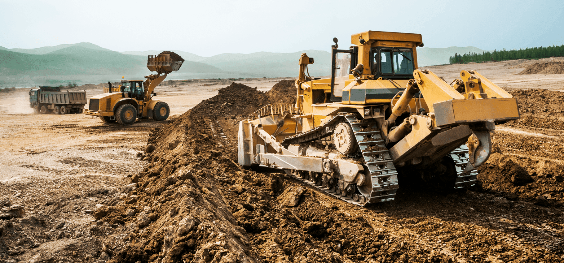 A large construction machine, like a wheel loader a filling the bucket with sand.